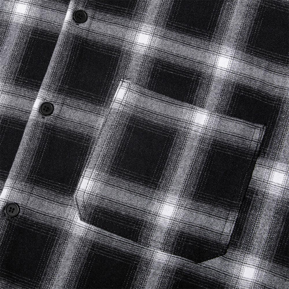 Close-up of black and white plaid flannel shirt fabric with pocket and buttons