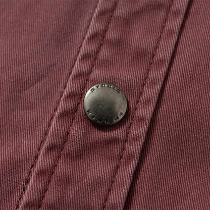 Close-up of metal snap button on brown textured fabric, detailed stitching visible