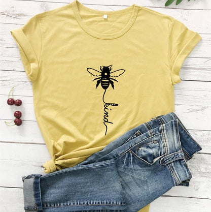 Yellow t-shirt with bee and 'kind' graphic, paired with blue jeans on white wood background