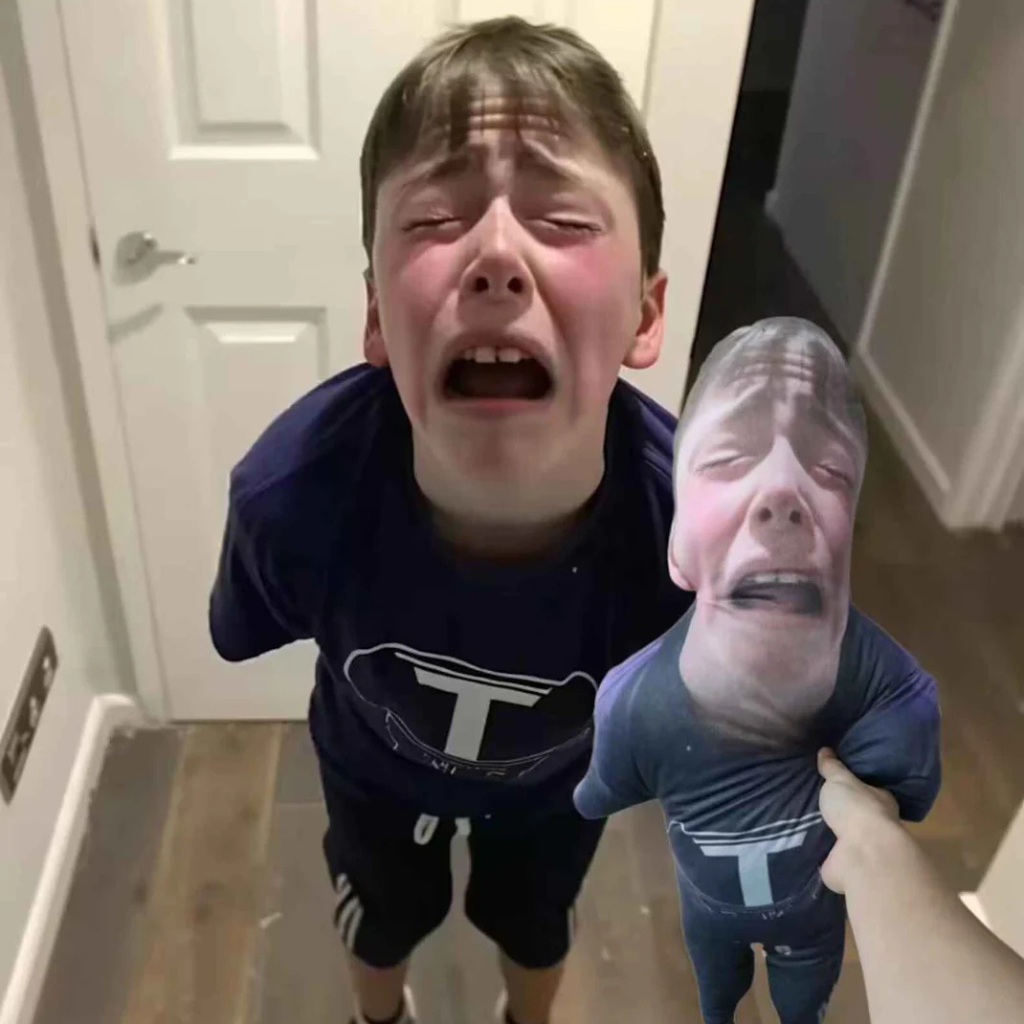 Child holding a cutout of their own face in front of a mirror