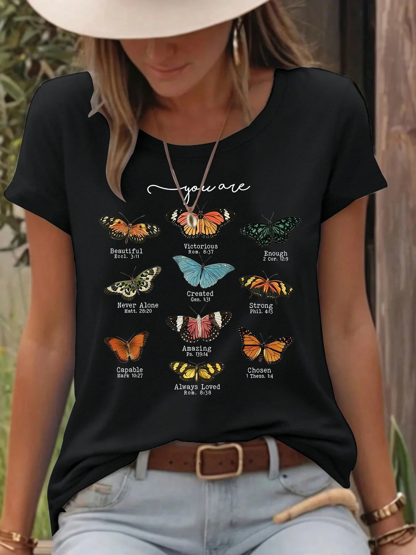 Woman wearing black t-shirt with colorful butterfly designs and positive Bible verse quotes