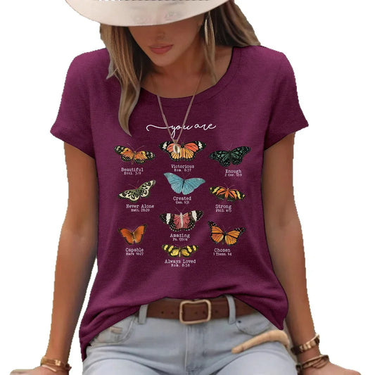 Woman wearing wine red t-shirt with colorful butterflies and empowering text outdoors