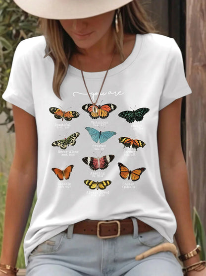 Woman in white t-shirt with colorful butterfly prints and inspirational text outdoors