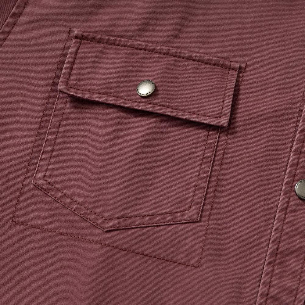 Close-up of a maroon fabric jacket pocket with flap and metallic snap button