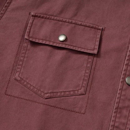 Close-up of a maroon fabric jacket pocket with flap and metallic snap button