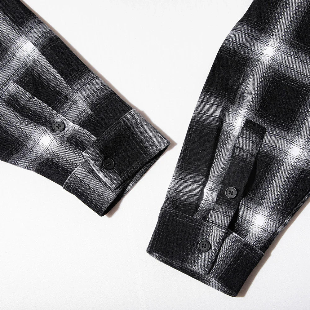 Close-up of black and white plaid flannel shirt sleeves with buttoned cuffs on white background