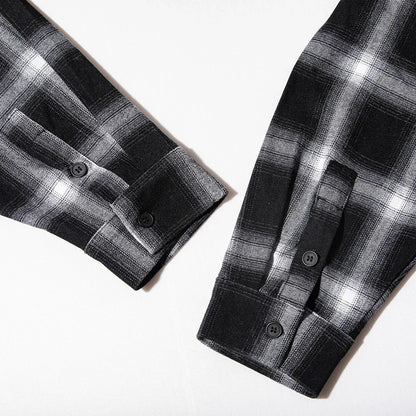 Close-up of black and white plaid flannel shirt sleeves with buttoned cuffs on white background