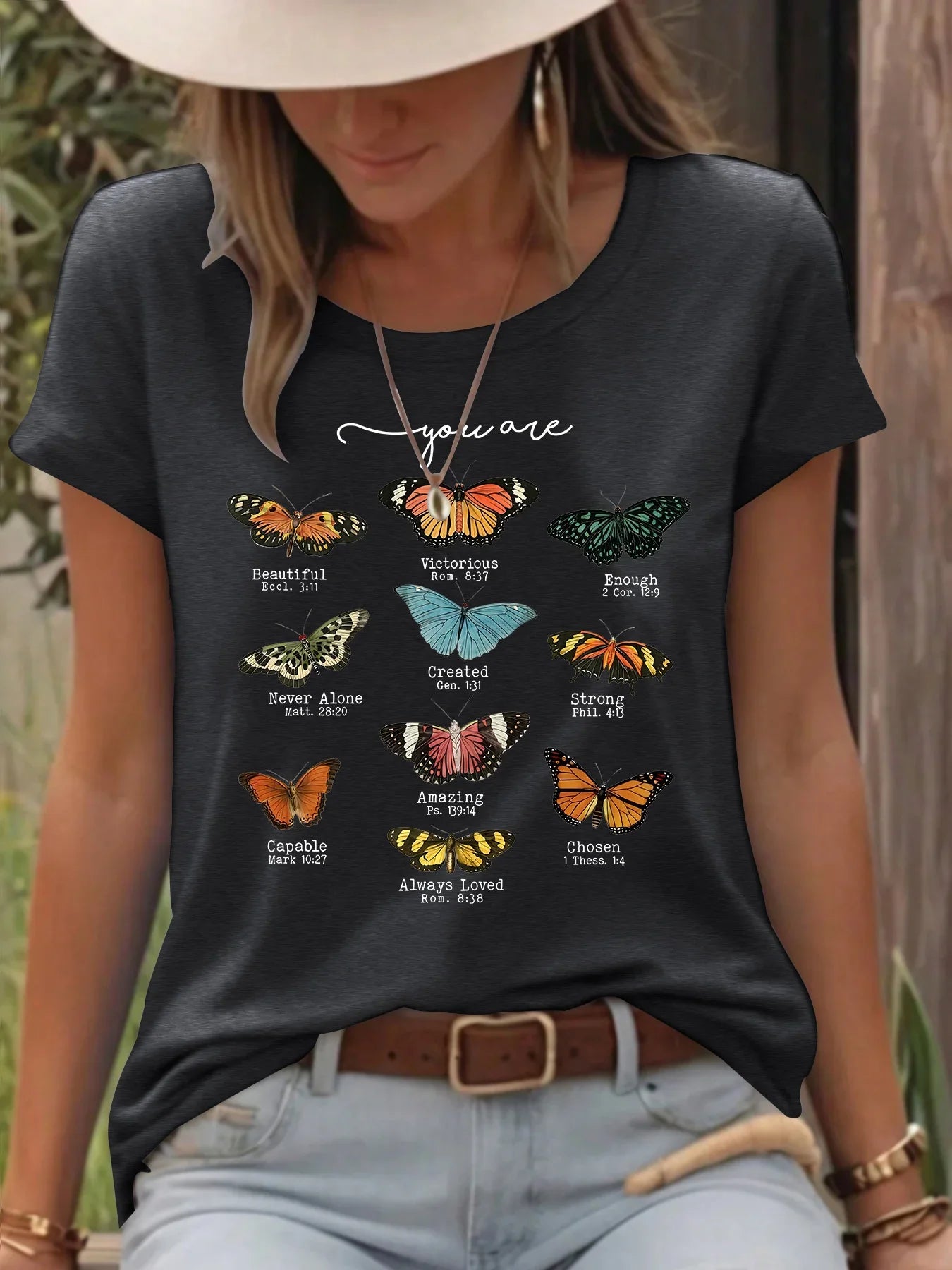 Woman wearing black t-shirt with colorful butterflies and inspirational Bible verses outdoors