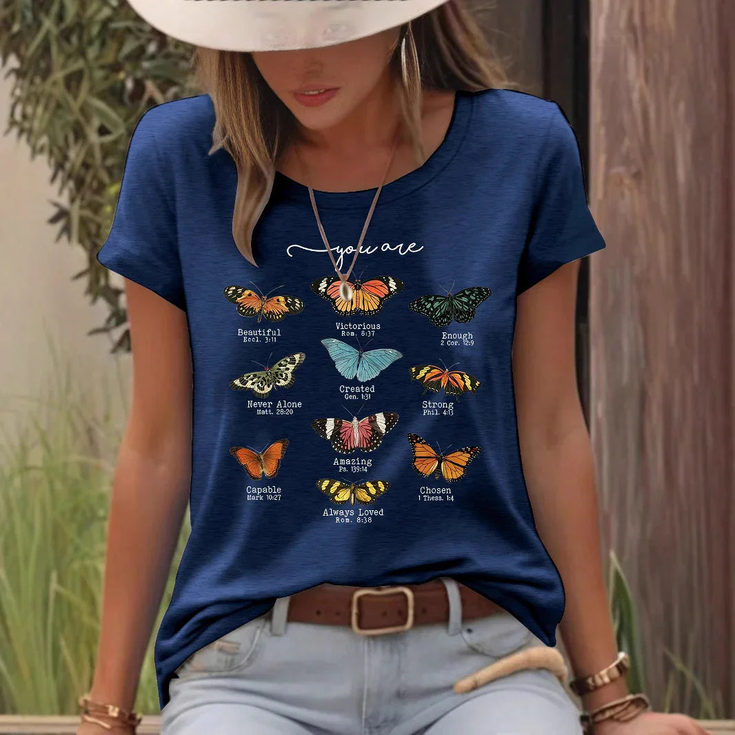 Woman wearing navy blue t-shirt with colorful butterfly graphic and positive affirmations outdoors