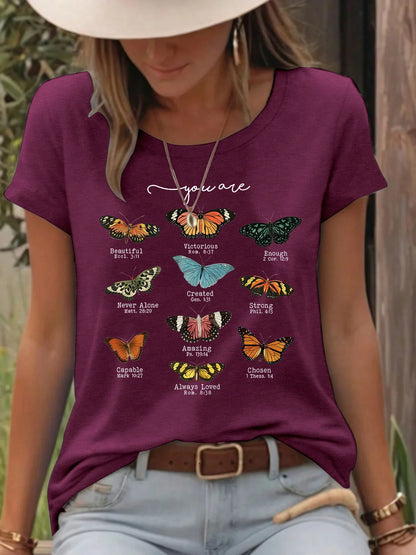 Woman wearing maroon t-shirt with colorful butterflies and inspirational words outdoors