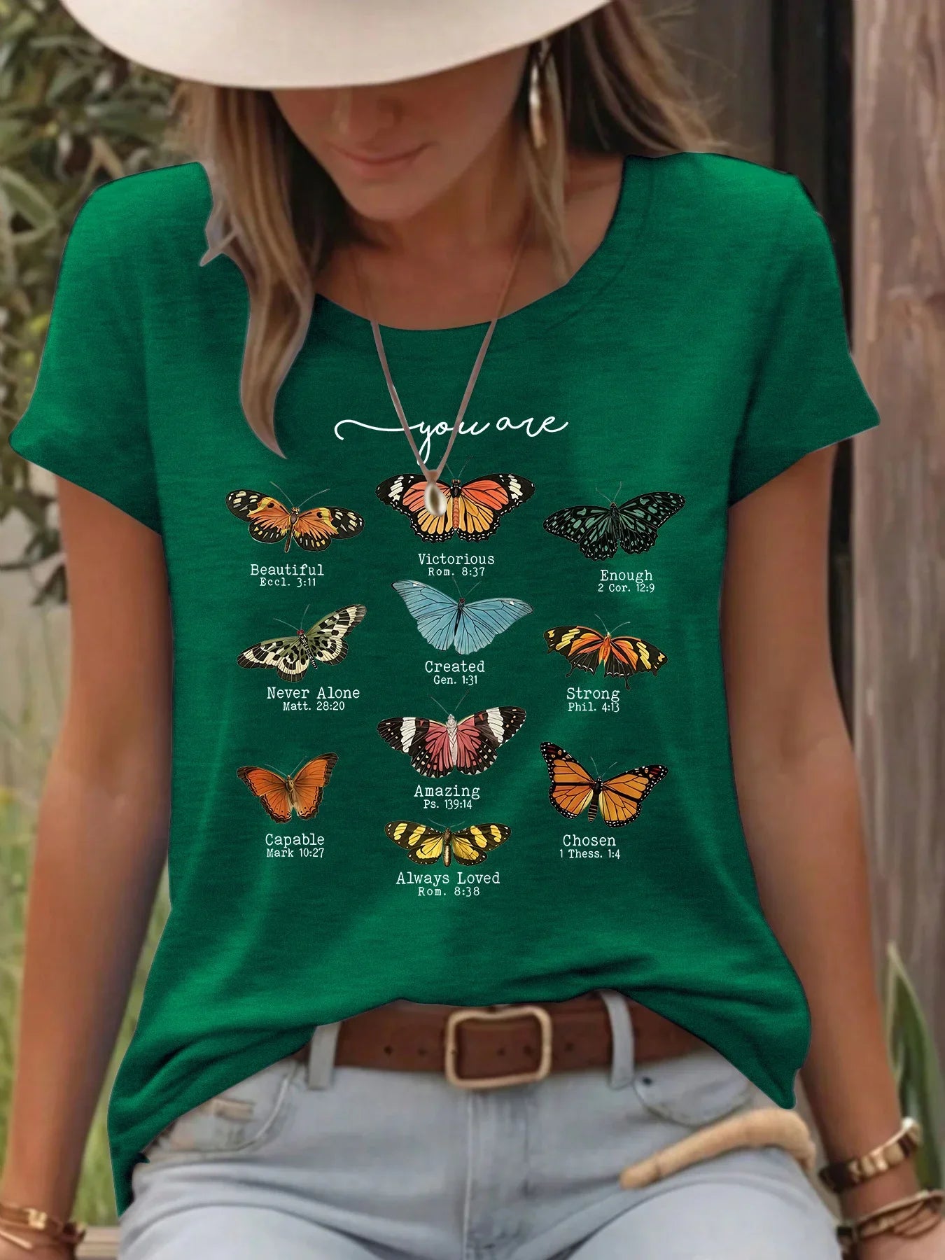 Woman wearing green t-shirt with colorful butterflies and inspirational Bible verses outdoors