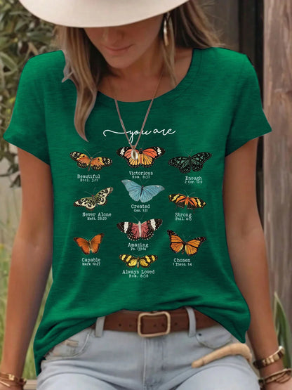 Woman wearing green t-shirt with colorful butterflies and inspirational Bible verses outdoors