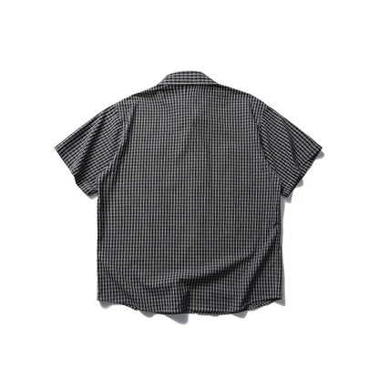 Black and white checkered short-sleeve shirt laid flat on white background