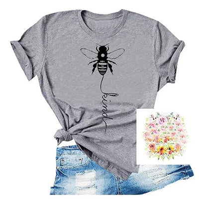 Gray t-shirt with bee and 'kind' graphic, paired with ripped denim shorts, floral accent.
